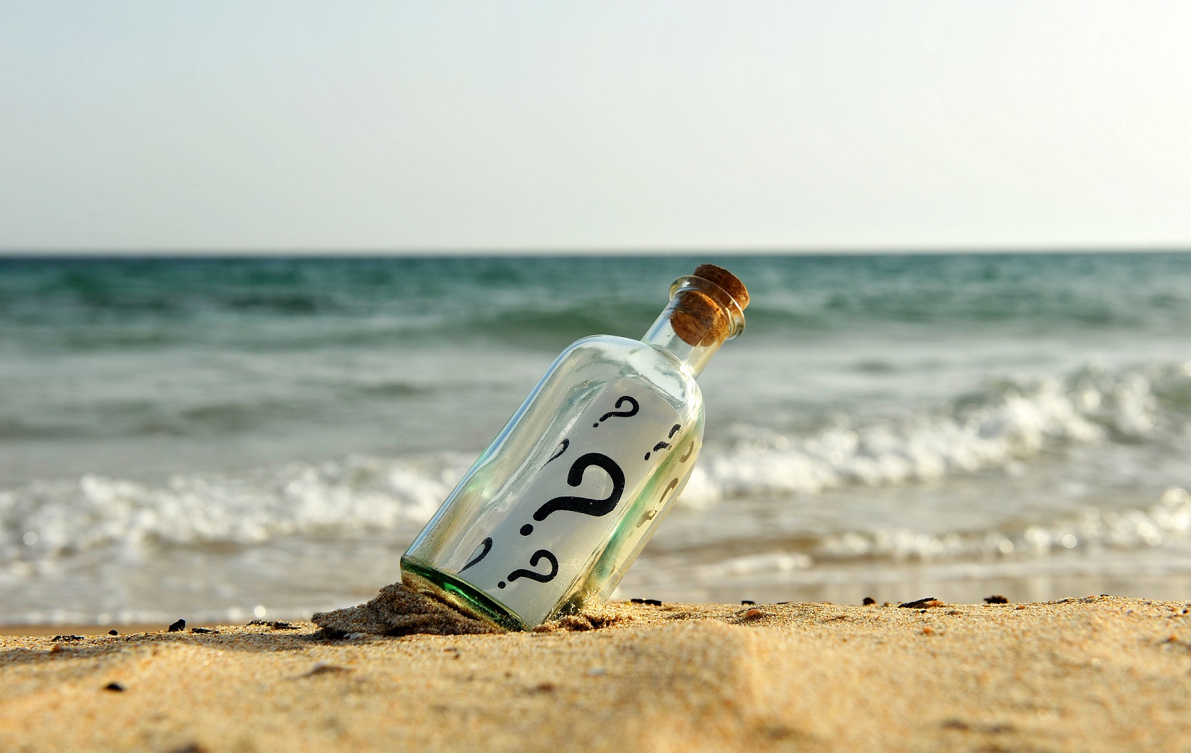Bottle with question on the beach